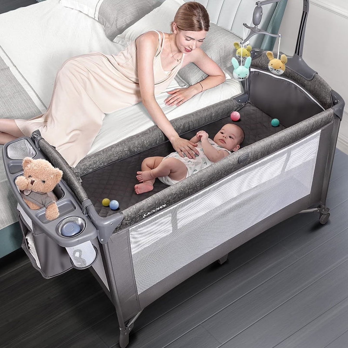 Babybond 3-in-1 Bedside Bassinet, Play Yard & Diaper Changer, suitable for newborns to toddlers aged 0-2. Comes with mattress, mosquito net, bottom diaper storage compartment and toy bar.Grey